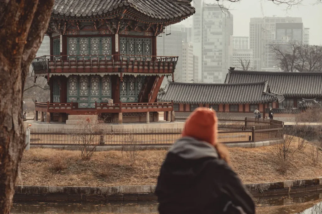 冬の景福宮で、ダウンとニット帽で池を眺める人Photo: Pexels